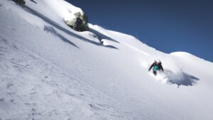 man skiing down a mountain in deep powder