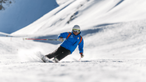 man carving on ski edge with blue jacket